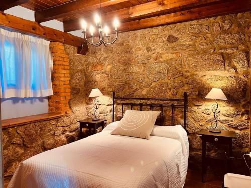 a bedroom with a bed in a stone wall at Villa Revolcona in La Adrada