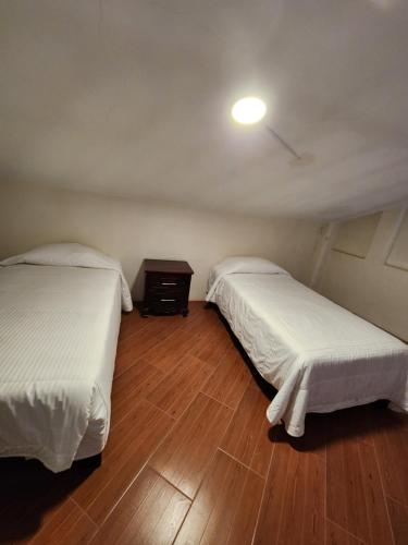 a room with two beds and a table with a light at HOSTAL HACIENDA APULCO in Huahuaxtla