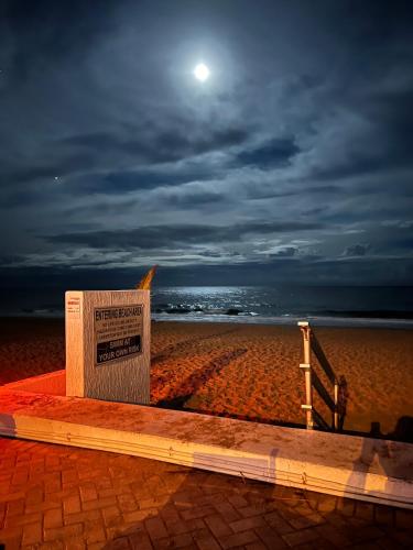 a sign sitting on the beach at night at Oceanview on SAND located in Ocean Manor Resort Fort Lauderdale Beach 2 bed 2 bath spacious corner unit partial ocean view in Fort Lauderdale