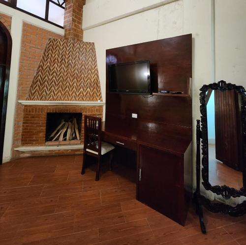 um quarto com uma secretária, uma televisão e uma lareira em HOSTAL HACIENDA APULCO 