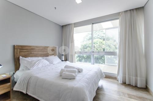 1 dormitorio con cama blanca y ventana grande en Elegant Villa Morra Apartment Bbqbalconygympool, en Asunción