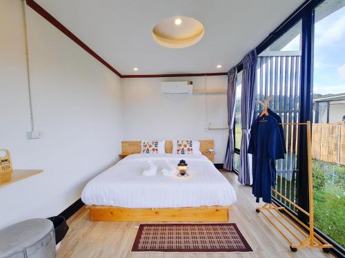 a bedroom with a bed and a large window at WC Coffee&ไร่หวานซึ้ง in Mae Hong Son