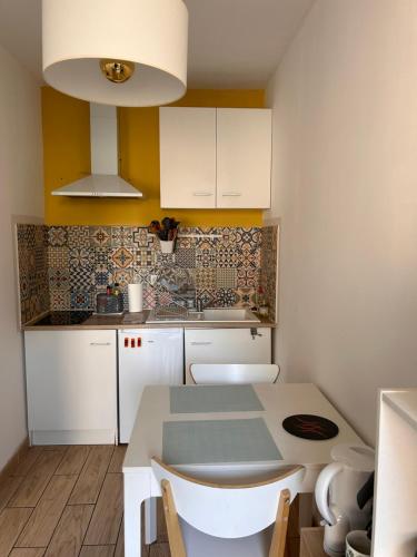 a kitchen with white cabinets and a table with chairs at Studio 30 m2 cocooning Timone Marseille in Marseille