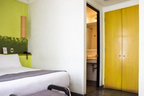 a bedroom with a white bed and a yellow door at Hotel Fundador in Santiago