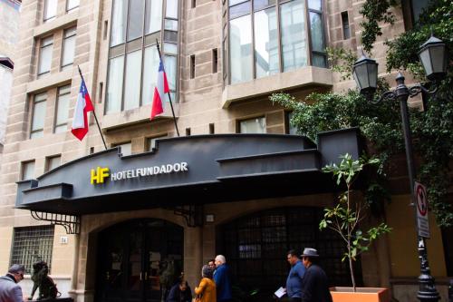 people walking outside of a building with two flags at Hotel Fundador in Santiago