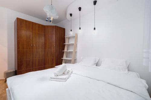 ヴロツワフにあるZabrodzka Family Apartmentの白いベッドと木製キャビネット付きのベッドルーム1室