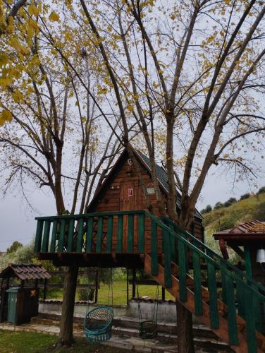 a tree house with a green bridge in front of a tree at Traditional Guesthouse in Tríkala
