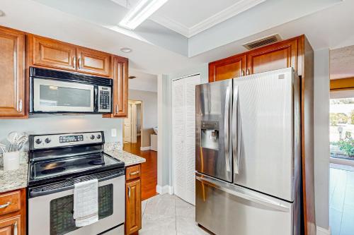 a kitchen with a stainless steel refrigerator and wooden cabinets at A Sunshine State of Mind in North River Shores
