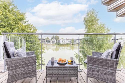 a balcony with a table and chairs and a view of a lake at Calm Waters HM95 HOT TUB Lakeside Spa Property in Somerford Keynes