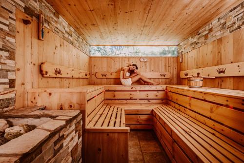 a woman sitting in a wooden sauna at Hotel Bergschlössl in Luson
