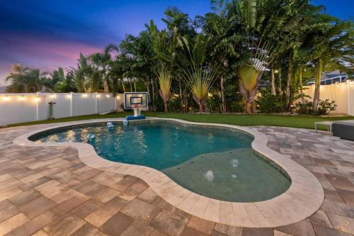 a pool with a basketball hoop in a backyard at Modern Pool Home w Putting Green in Largo