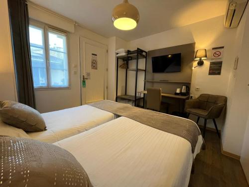 a hotel room with two beds and a desk at Cit'Hotel Le Cheval Blanc, Cognac Centre in Cognac