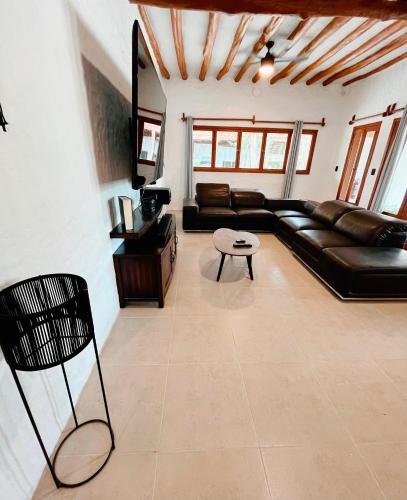 a living room with a black leather couch and a table at Casa Arena Holbox! in Holbox Island