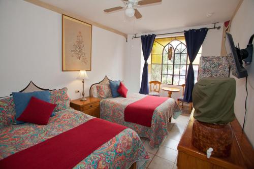 a bedroom with two beds and a tv and a window at Hotel Casa Blanca in Ajijic