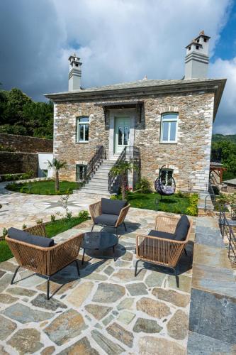 a stone house with chairs and a patio at Nostos Country House in Tsagarada