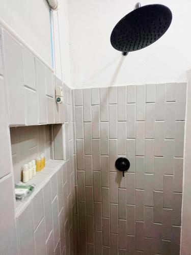 a bathroom with a shower with white tiles and a light at Arena Apartment 1 in Holbox Island