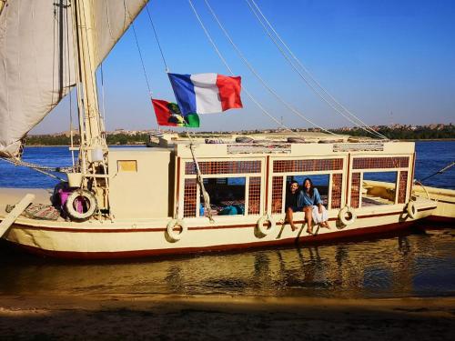 two people sitting on a boat with flags on it at Aswan Nile Felucca hotel in Aswan