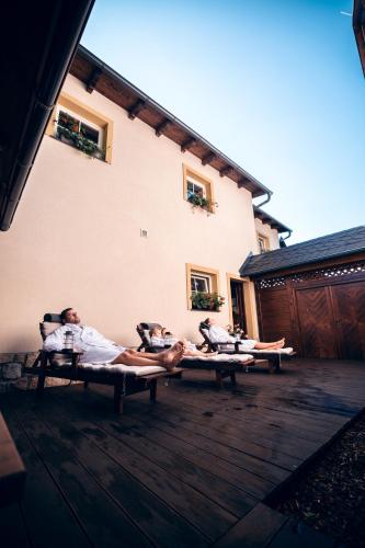 three people laying on benches outside of a building at Apartmány nad stájemi - Jítravský Dvorec in Rynoltice