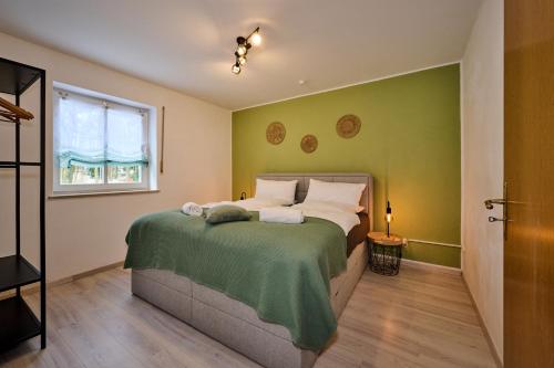 - une chambre avec un lit aux murs verts et une fenêtre dans l'établissement apanoxa homes I zentral I Parkplätze I Deluxe Apartment, à Straubing