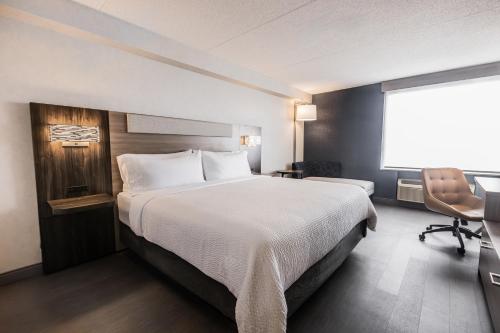 a hotel room with a large bed and a chair at Holiday Inn Express Toronto-North York by IHG in Toronto