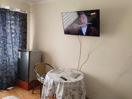 Habitación con mesa y TV colgada en la pared. en Hostal Donde Gabriel, en Chillán