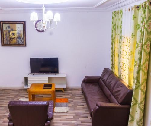 een woonkamer met een bank en een tv bij E&T Resorts in Buea