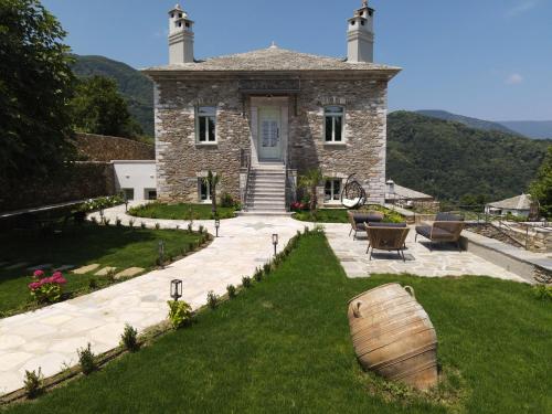 a large stone house with a barrel in front of it at Nostos Country House in Tsagarada