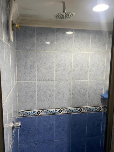 y baño con ducha de azulejos azules. en Hostel Kumho Home, en Medellín