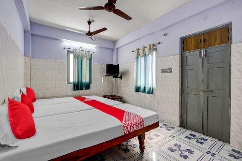 a bedroom with a bed with red pillows and a door at OYO Flagship Sai Ganesh Deluxe Lodge in Tirupati