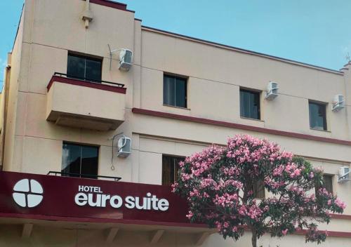 un edificio con un cartel delante de un árbol en Hotel Euro Suite Poços de Caldas By Nacional Inn, en Poços de Caldas