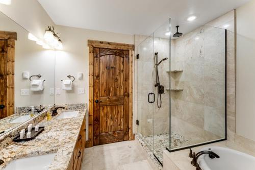 a bathroom with two sinks and a shower with a glass door at Experience Montana Cabins - Lake View Luxury Cabin #7 in Bigfork