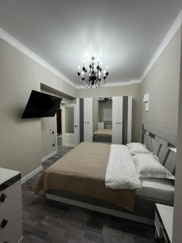 a bedroom with a large bed and a chandelier at Рахат апарт in Aktobe