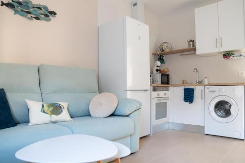 a living room with a blue couch and a kitchen at Apartamentos Barlovento in Puerto de Mazarrón