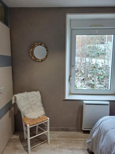 a bedroom with a mirror and a chair and a window at Entre Montagnes et Lacs in La Bresse