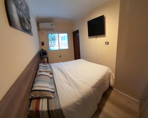 a bedroom with a bed and a tv on the wall at Tranquilidad Total in Roldán