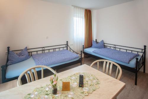 a room with two beds and a table and chairs at Privatpension zur Schwarzach in Greding