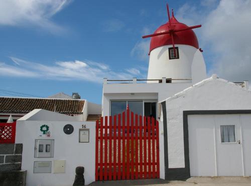 a lighthouse with a red gate in front of it at Moinho Mó da Praia in Praia da Graciosa