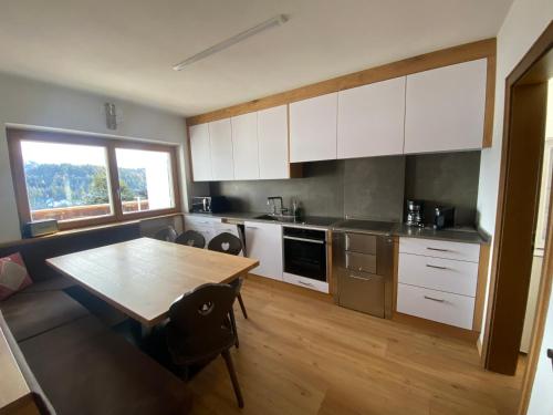 a kitchen with white cabinets and a wooden table at Ampio appartamento di 200mq nel cuore di Antermoia in Antermoia