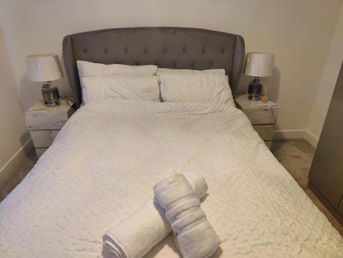 a large white bed with a towel on it at 2 bedroom en-suite apartment in Basildon, Essex (Enjoy the simple things in life) in Laindon