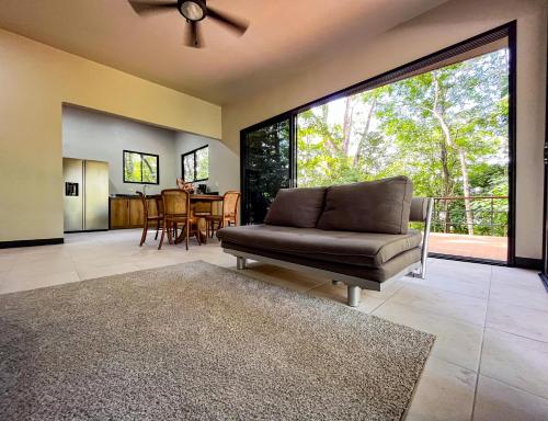 a living room with a couch and a large window at Selva Pacific Mountain Beach retreat in Quebrada Ganado