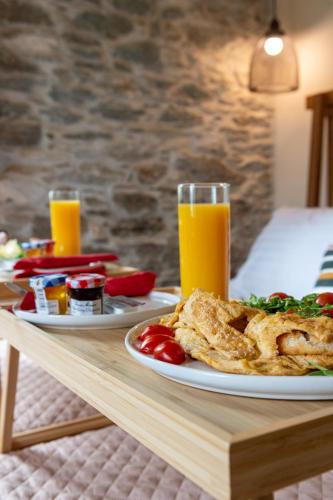 a table with two plates of food and two glasses of orange juice at Nostos Country House in Tsagarada