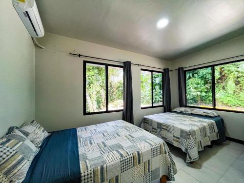 a bedroom with two beds and two windows at Selva Pacific Mountain Beach retreat in Quebrada Ganado