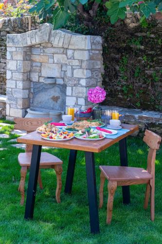 a picnic table with food on it with two chairs at Nostos Country House in Tsagarada