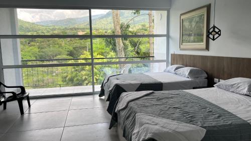 two beds in a room with a large window at Villa La Felisa Hospedaje Campestre Pandi Cundinamarca in Pandi
