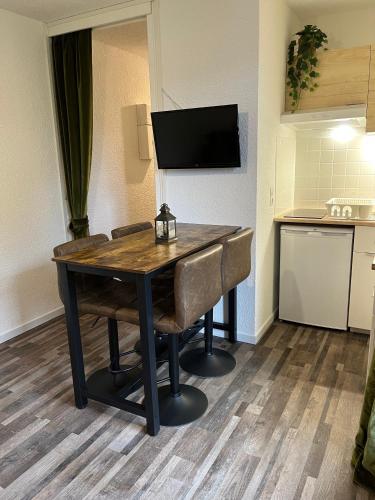 une table à manger avec des chaises et une télévision dans l'établissement La Tanière de Sven - Vue Montagne, à Saint-Nicolas-la-Chapelle