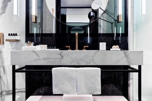 uma casa de banho com um balcão de mármore e um espelho. em Academias Hotel, Autograph Collection em Atenas