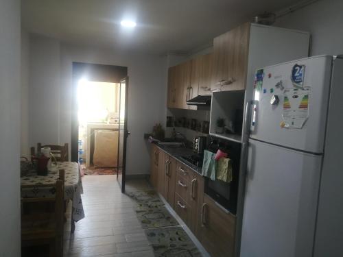 a kitchen with a white refrigerator and wooden cabinets at F3 haut standing in Oran