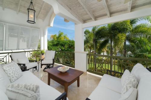 a living room with white furniture and a balcony with palm trees at Royal Westmoreland - Sugar Cane Ridge 3 townhouse in Saint James