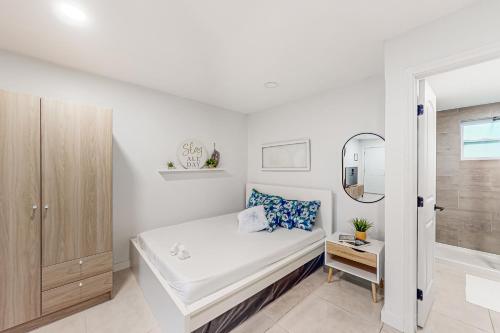 a white bedroom with a bed and a mirror at Welcome to Paradise #2 in Fort Lauderdale