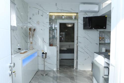 een badkamer met een tv en een witte muur bij Holiday Home Litteri in Catania